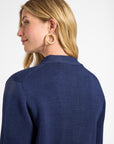 Woman wearing a navy blue sweater with a plain white background