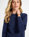 Woman wearing a navy blue crewneck sweater on a white background