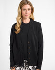 Woman wearing a black cardigan over a black top with floral shorts on a white background