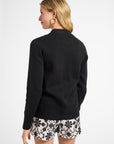 Woman wearing a black cardigan and floral shorts on a white background