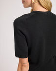 Person wearing a black sweater on a plain background