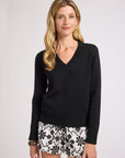 Woman modeling a long sleeve, black, v-neck sweater on a white backdrop