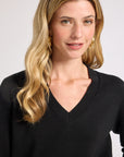 Woman wearing a black sweater against a plain background