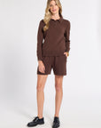 Woman modeling a brown cashmere polo on a white background