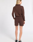 Woman modeling a brown cashmere sweater on a white background
