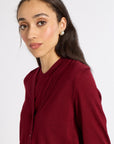 Close up of a woman modeling a red cardigan on a white backdrop
