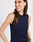 A woman wearing a sleeveless navy blue sleeveless top, shown from the chest up against a light gray studio background.