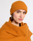 Woman modeling an orange 100% cashmere hat in a studio