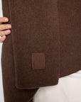 Close View: Woman wearing a chocolate brown wrap with a leather embossed tag.