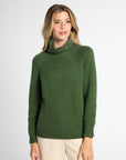 Front view: Woman wearing Forest Green boyfriend turtleneck sweater in front of white background.