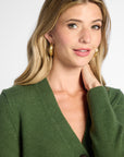 Close view: Woman wearing Forest Green v-neck button up cardigan in front of white background.