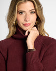 Close up view of woman in wine-colored boyfriend turtleneck sweater in front of a white background.