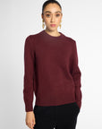 Front view of woman in wine-colored crew neck cardigan in front of a white background.
