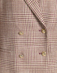 Close-up of a double-breasted blazer in a beige and dusty rose plaid pattern, featuring gold buttons.