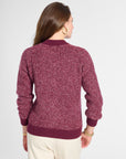 A woman shown from the back wearing a marled burgundy knit sweater and cream pants against a light gray studio background.