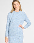 A woman modeling a light blue tweed long-sleeve midi dress with button details down the front and black knee-high boots, set against a plain light gray studio background.