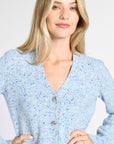 A woman wearing a light blue long-sleeve cardigan sweater with a blue and white speckled pattern, featuring a V-neck and button-front closure.