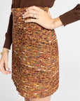 Woman modeling a brown tweed skirt with a long sleeve black blouse in a studio