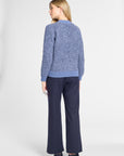 A woman is shown from the back wearing a textured heathered blue sweater and navy wide-leg trousers against a light gray studio background.