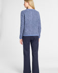A woman shown from the back wearing a textured heathered blue knit sweater and navy blue wide-leg trousers, photographed against a light gray studio background.