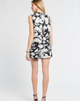 Woman dressed in a sleeveless black and white floral blouse on a white background