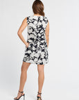 Woman wearing a sleeveless dress with black and white floral pattern on a white background