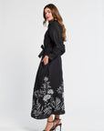 Woman wearing a black dress with white floral patterns on a white background