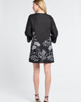 Woman wearing a black dress with floral patterns on a white background