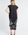 woman wearing a black caftan with black heels on a white backdrop