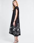 Woman wearing a black dress with floral patterns on a white background