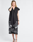 Woman wearing a black dress with white floral patterns on a white background
