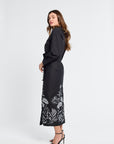 Woman wearing a black dress with floral patterns on a white background