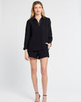 Woman wearing a black blouse and shorts on a white background