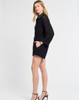 Woman wearing a black blouse and shorts with lace details on a white background