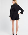 Woman wearing a black lace blouse and shorts white background