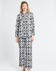 Woman wearing a black and white floral blouse and pants on a white background