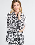 Woman wearing a black and white floral long sleeve button down blouse on a light gray background