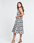 Woman wearing a black and white floral midi dress with black heels on a white background