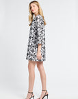 Woman wearing a black and short white floral dress on a white background