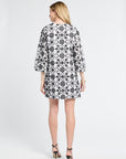 Woman modeling a black and white floral detailed dress on a white background