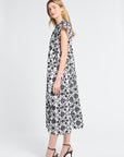 Woman wearing a black and white floral caftan and black heels on a white background