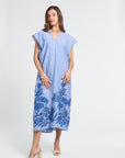 Woman wearing a blue caftan with floral embroidery on a white background