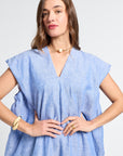 Woman wearing a light blue v-neck caftan against a white background