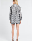 Woman wearing a floral patterned blouse and matching shorts on a white background