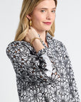 Woman modeling a black floral patterned blouse on a white background