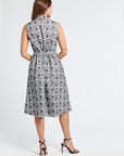 Woman wearing a sleeveless mid-length floral dress on a white background