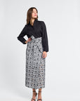 Woman wearing a black and white embroidered patterned skirt on a white background