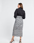 Woman modeling a black blouse and floral skirt on a white background