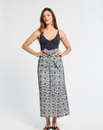 Woman wearing a black top and floral embroidered skirt on a white background