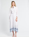 Woman wearing a white dress with lace trim on the bottom against a white background
